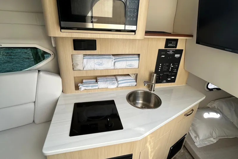 Slide: The Image of 2024 Regal 26 XO boat interior with kitchenette, sink, and microwave. - 22