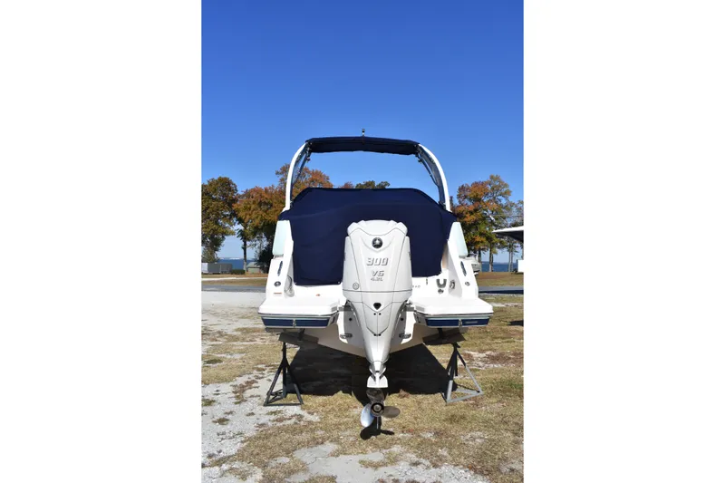 Slide: The Image of 2024 Regal 26 XO boat with covered outboard motor, parked on grass under clear blue sky. - 3