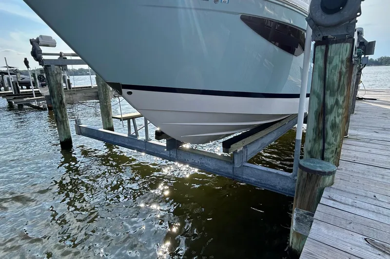 Slide: The Image of 2024 Regal 26 XO boat on a lift at a dock, reflecting sunlight on water. - 6