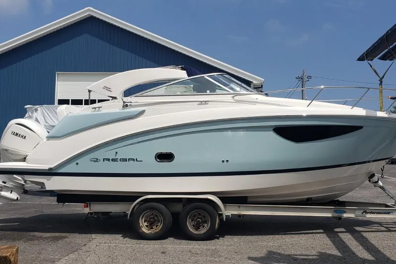 Slide: The Image of 2024 Regal 26 XO boat on trailer, side view, blue and white design. - 7