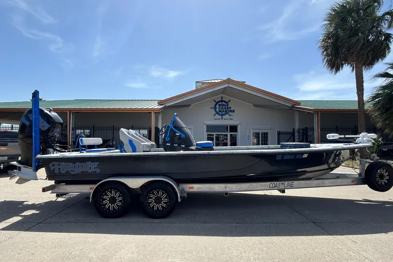 The Image of 2015 Haynie Magnum boat on trailer outside a marine dealership under a clear sky. - 1