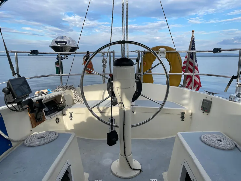 Slide: The Image of Cockpit of 1980 Lancer 36 sailboat with steering wheel, American flag, and ocean view. - 17