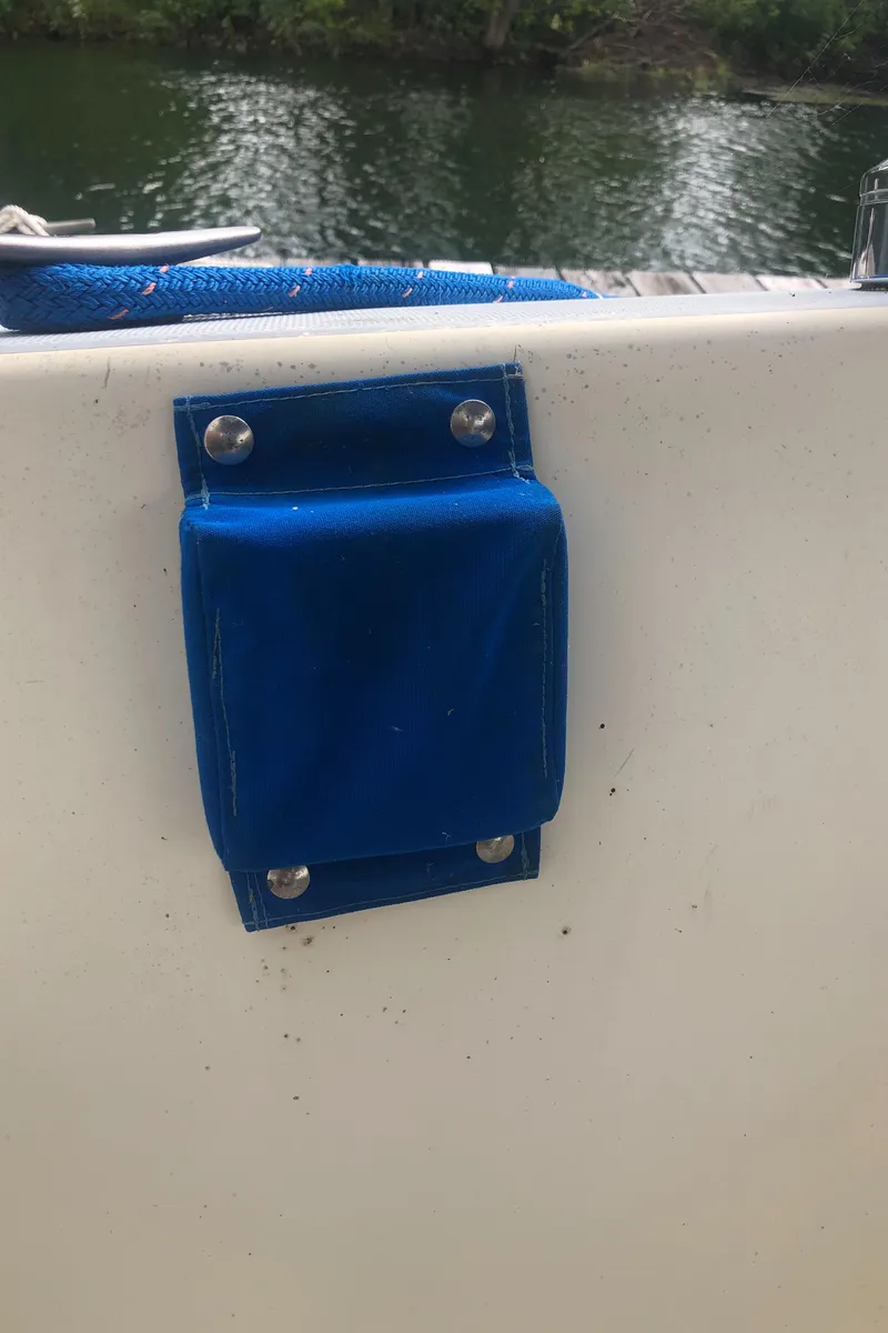 Slide: The Image of Blue fabric pocket on 1980 Lancer 36 boat railing by water. - 19