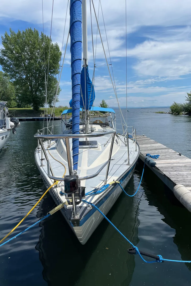 Slide: The Image of 1980 Lancer 36 sailboat docked on a calm lake under a clear blue sky. - 3
