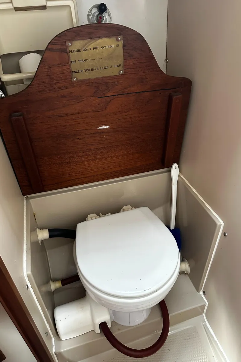 Slide: The Image of 1980 Lancer 36 boat bathroom with toilet, wooden panel, and cleaning brush. - 35