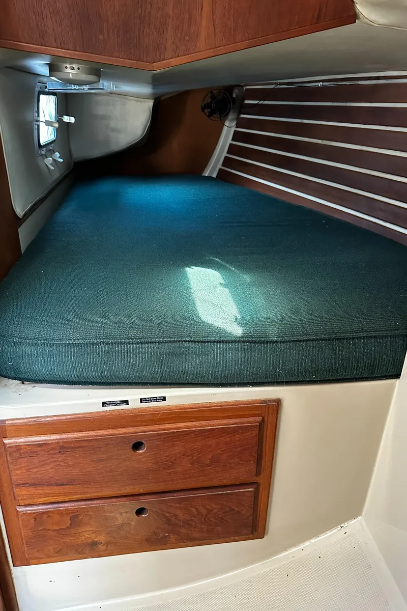 Slide: The Image of 1980 Lancer 36 interior cabin with green cushioned berth and wooden drawers. - 40