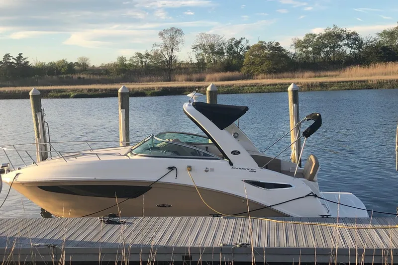 Slide: The Image of 2016 Sea Ray Sundancer 260 docked on a serene lake with trees in the background. - 2