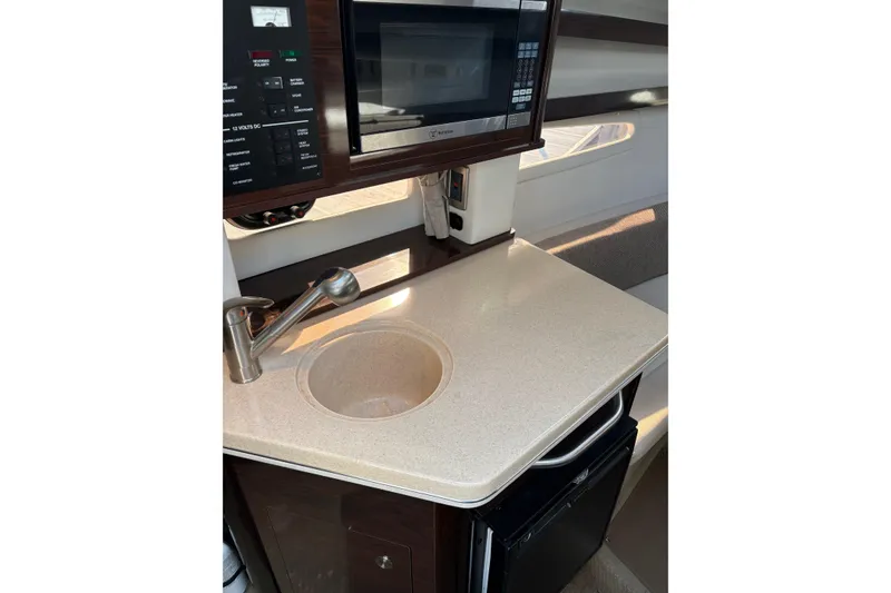 Slide: The Image of 2016 Sea Ray Sundancer 260 galley with sink, microwave, and compact fridge. - 3