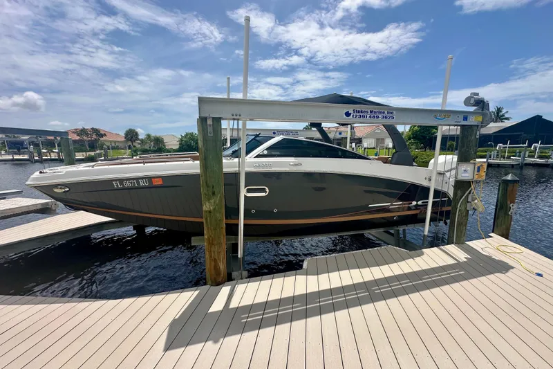 Slide: The Image of 2019 Four Winns HD270 OB boat docked on a lift under a sunny sky. - 22
