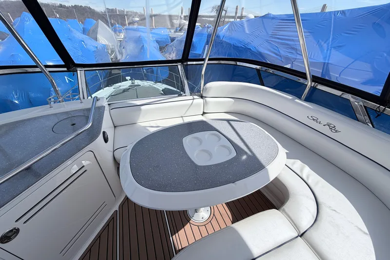 Slide: The Image of 2006 Sea Ray 52 Sedan Bridge yacht interior with seating and table, surrounded by blue tarps. - 15