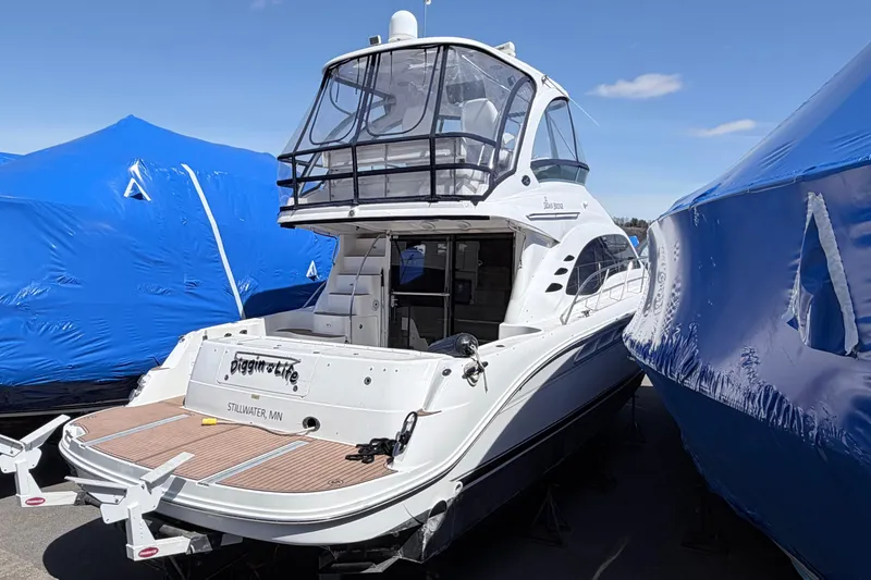 Slide: The Image of 2006 Sea Ray 52 Sedan Bridge yacht docked, surrounded by blue tarps under a clear sky. - 2