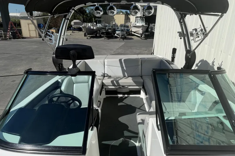 Slide: The Image of 2020 MasterCraft NXT22 boat interior with seating and steering wheel, parked outdoors. - 13