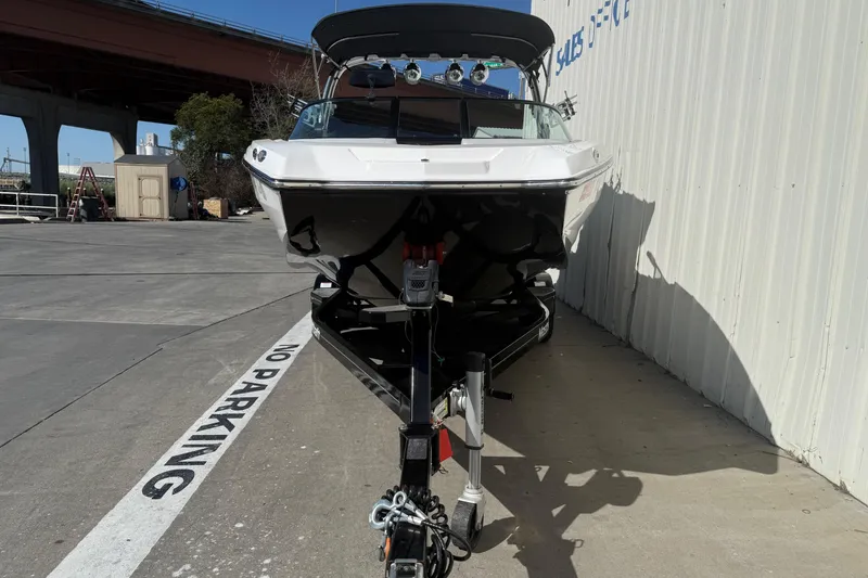 Slide: The Image of 2020 MasterCraft NXT22 boat on trailer, parked beside a building. - 2