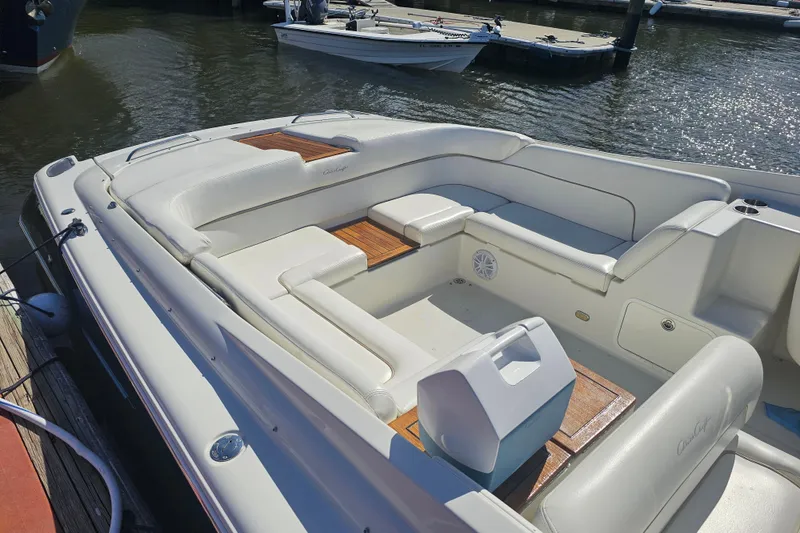 Slide: The Image of 2003 Chris-Craft Launch 28 boat with white seating and wooden accents docked by the water. - 12