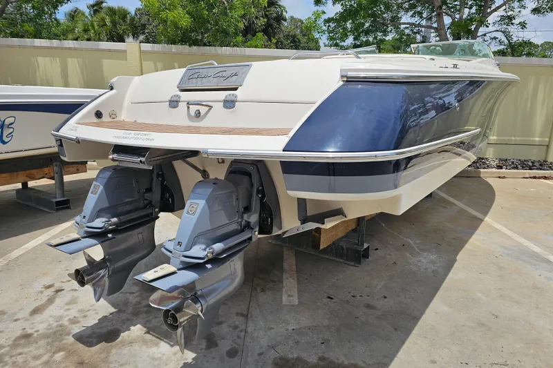 Slide: The Image of 2003 Chris-Craft Launch 28 boat cruising on calm waters near modern buildings. - 9