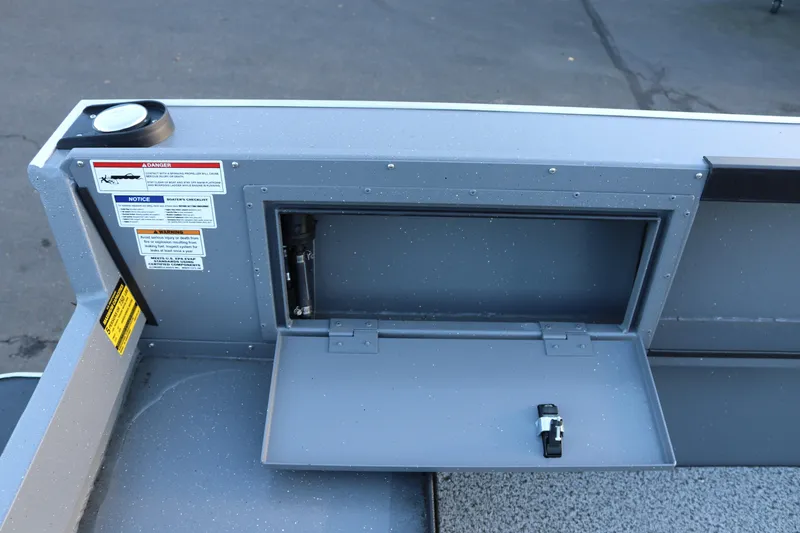 Slide: The Image of 2026 Alumaweld Adventurer 20 boat storage compartment with safety labels and latch. - 13