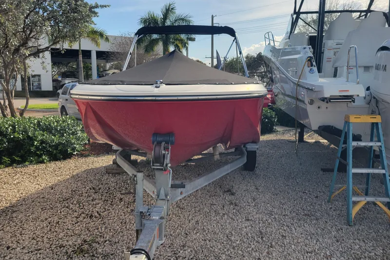 The Image of 2022 Bayliner Element M17 boat on trailer, red hull, parked outdoors. - 1