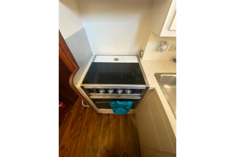 Slide: The Image of Compact kitchen area in a 1988 Hatteras 40 Double Cabin yacht with stove and sink. - 13