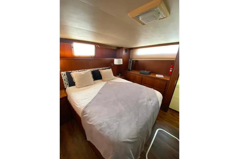 Slide: The Image of Cozy bedroom in 1988 Hatteras 40 Double Cabin yacht with wood paneling and soft lighting. - 29