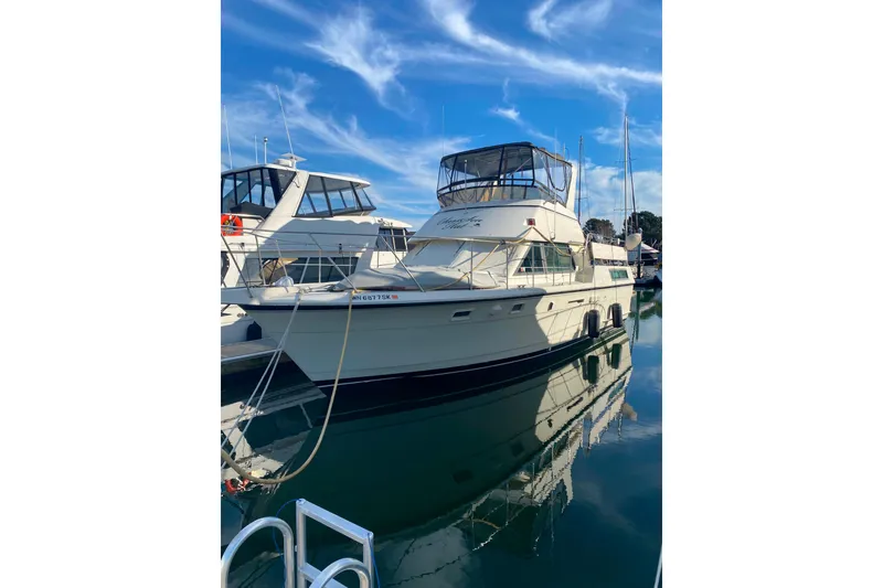 Slide: The Image of 1988 Hatteras 40 Double Cabin yacht docked in a marina under a clear blue sky. - 74
