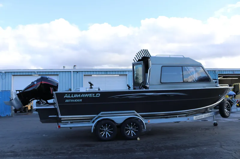 Slide: The Image of 2026 Alumaweld Intruder Hard Top 24 boat on trailer, parked outside a blue building. - 4