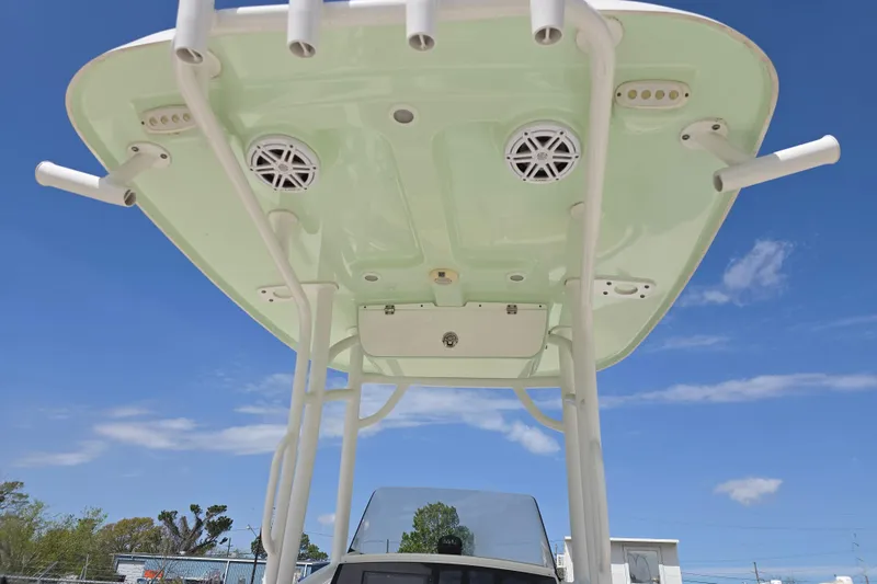 Slide: The Image of 2020 Sportsman Heritage 211 Center Console T-top with rod holders and speakers under blue sky. - 18