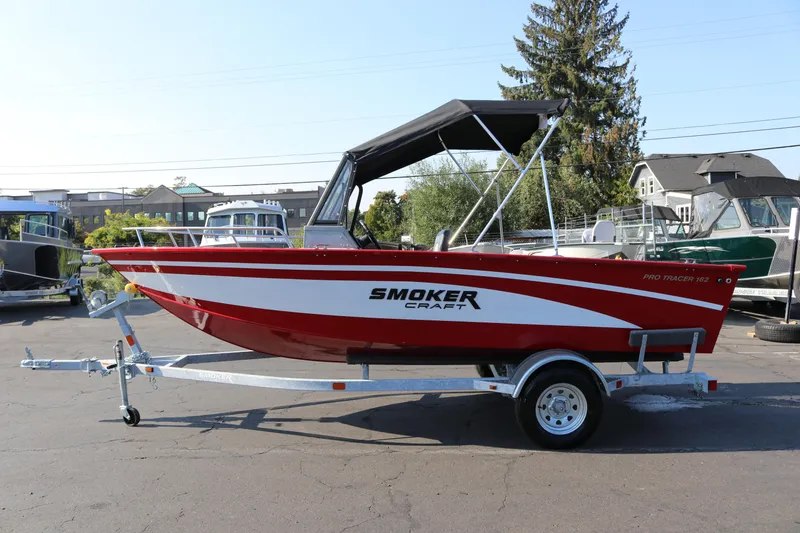The Image of Red 2026 Smoker Craft Pro Tracer 162 boat on trailer, parked outdoors. - 1