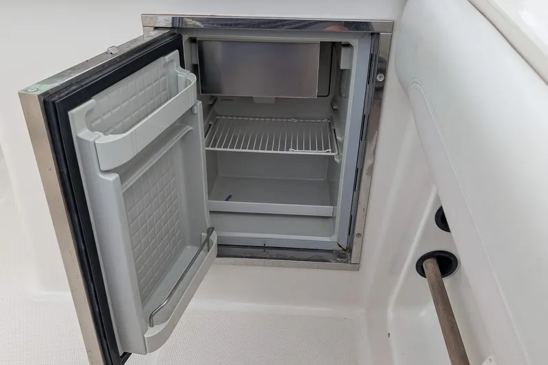 Slide: The Image of Open mini fridge on 2014 Sailfish 275 DC boat, showing interior shelves. - 10