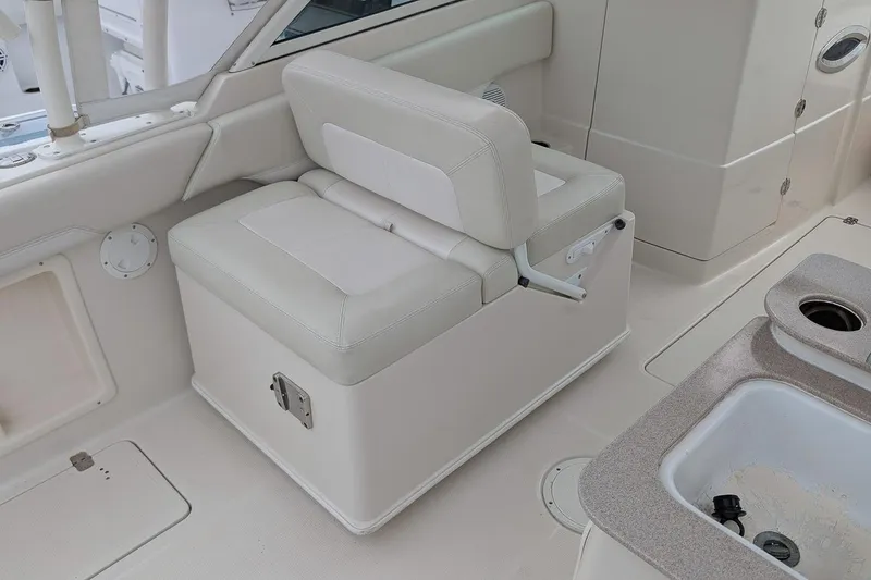 Slide: The Image of 2014 Sailfish 275 DC boat interior with white seating and storage compartment. - 11