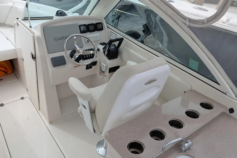 Slide: The Image of 2014 Sailfish 275 DC boat cockpit with steering wheel, Garmin display, and cup holders. - 14