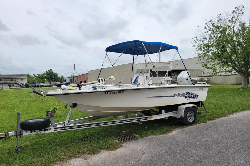 Slide: The Image of 2004 Sea Chaser 1950 RG boat on trailer with blue canopy in grassy area. - 9