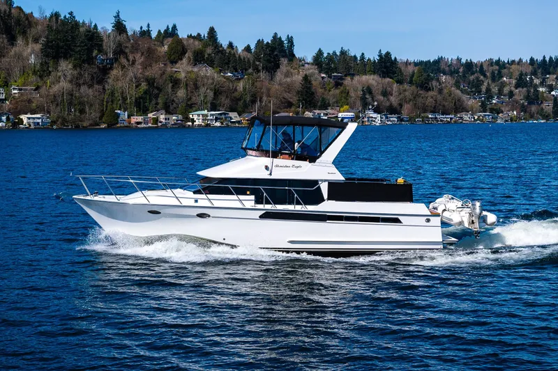 Slide: The Image of 1989 Ocean Alexander 42 yacht cruising on a scenic lake with forested shoreline. - 10