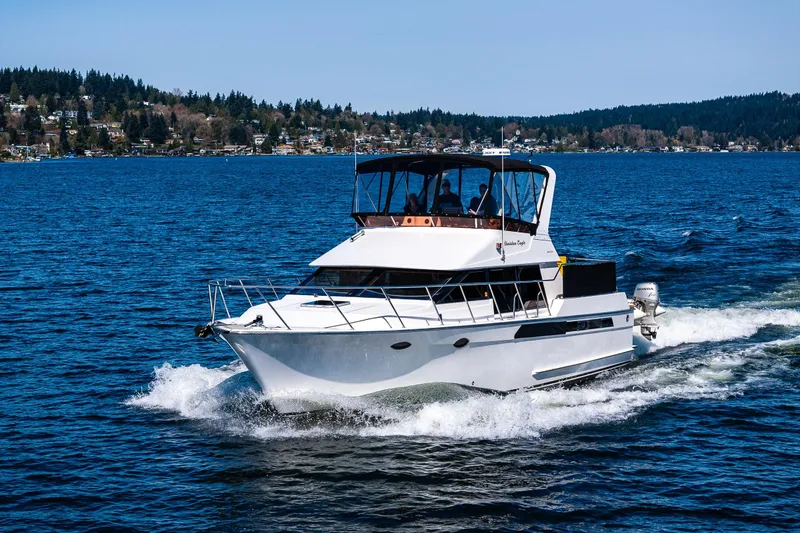 Slide: The Image of 1989 Ocean Alexander 42 yacht cruising on a scenic lake with forested shoreline. - 15