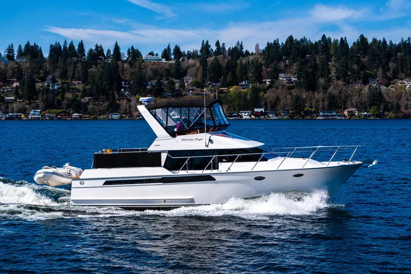 Slide: The Image of 1989 Ocean Alexander 42 yacht cruising on a scenic lake with forested shoreline. - 17