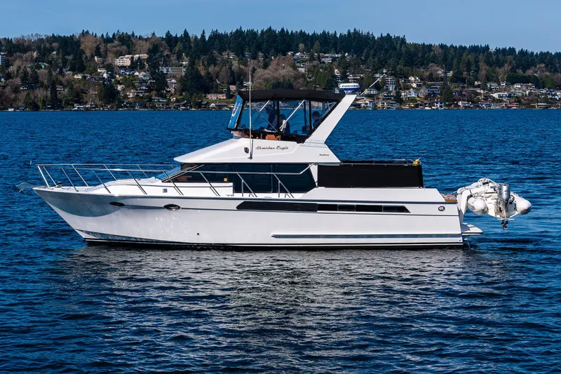 Slide: The Image of 1989 Ocean Alexander 42 yacht on a serene lake with forested shoreline. - 20