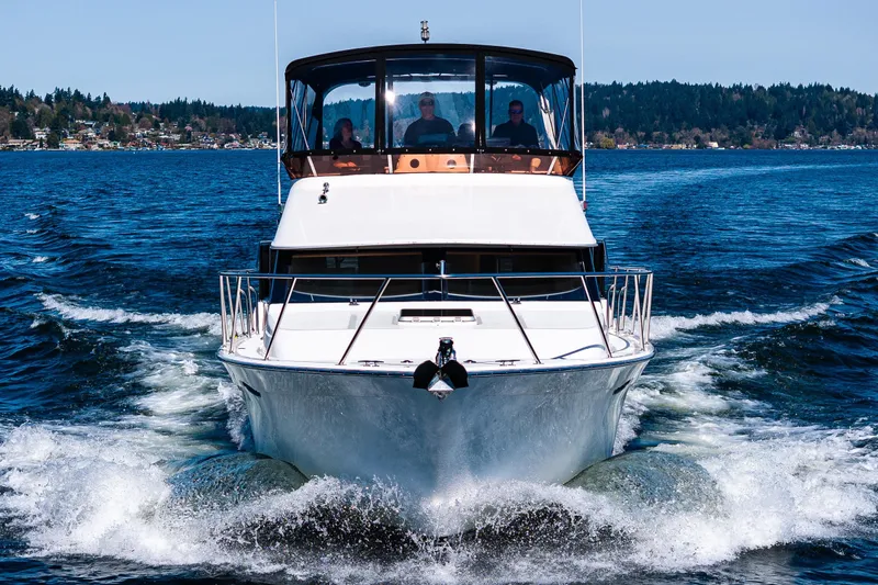 Slide: The Image of 1989 Ocean Alexander 42 yacht cruising on a scenic lake with forested shoreline. - 21