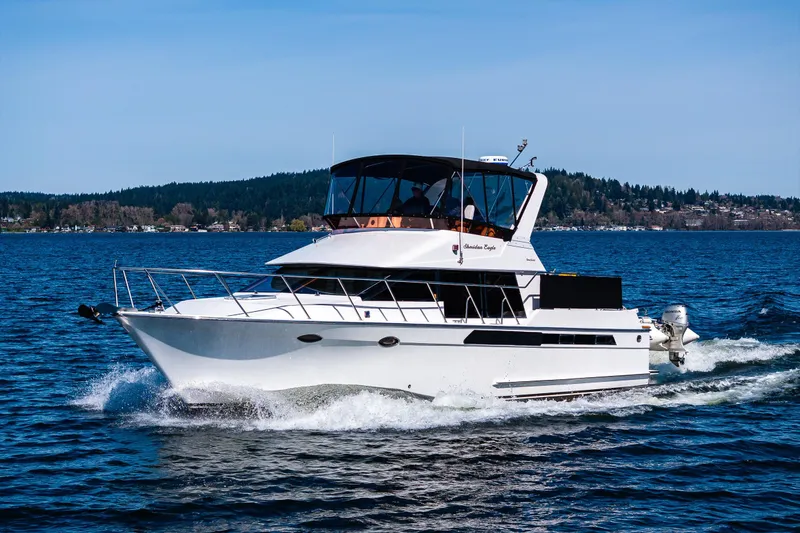 Slide: The Image of 1989 Ocean Alexander 42 yacht cruising on a scenic lake with forested shoreline. - 22