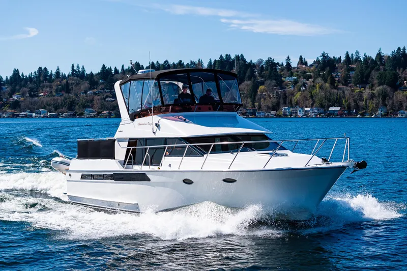 Slide: The Image of 1989 Ocean Alexander 42 yacht cruising on a scenic lake with forested shoreline. - 23