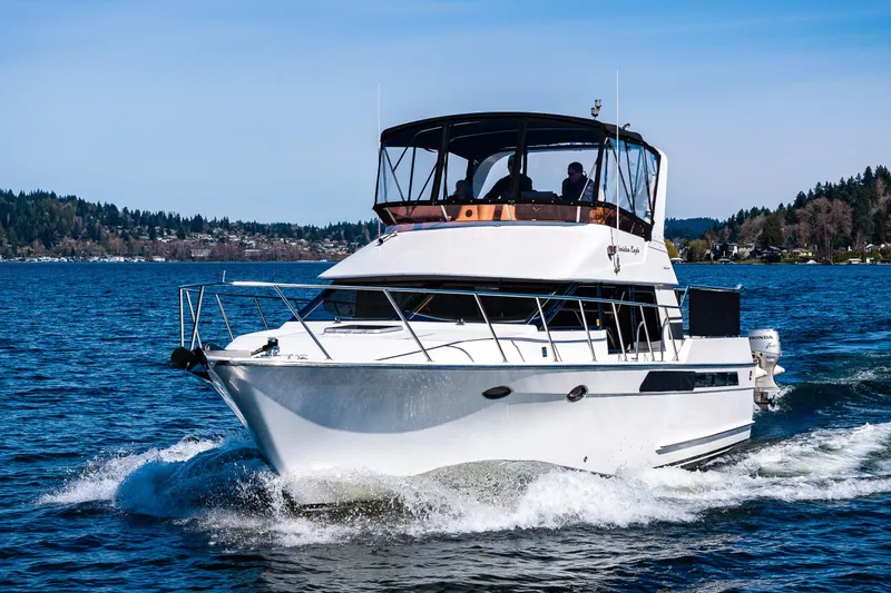 Slide: The Image of 1989 Ocean Alexander 42 yacht cruising on a scenic lake with forested shoreline. - 24