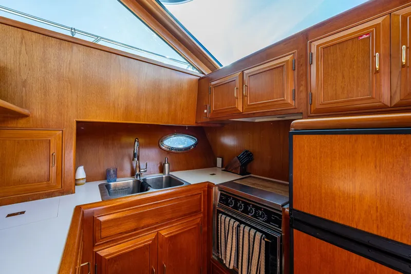 Slide: The Image of 1989 Ocean Alexander 42 yacht kitchen with wood cabinetry, sink, stove, and refrigerator. - 56