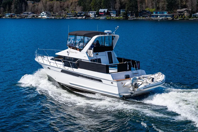 Slide: The Image of 1989 Ocean Alexander 42 yacht cruising on a serene lake with waterfront homes. - 6