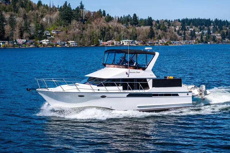 Slide: The Image of 1989 Ocean Alexander 42 yacht cruising on a scenic lake with forested shoreline. - 8