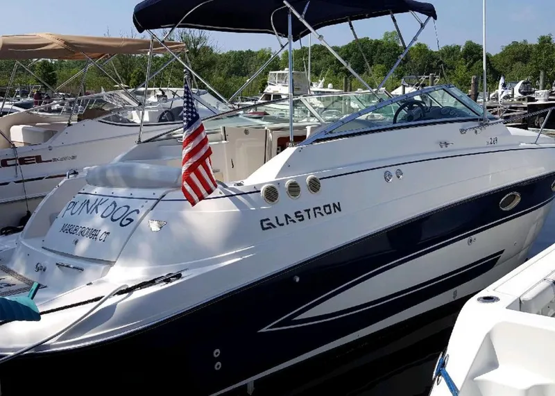 Slide: The Image of 2006 Glastron GS 269 boat on stands, parked outdoors under a cloudy sky. - 6