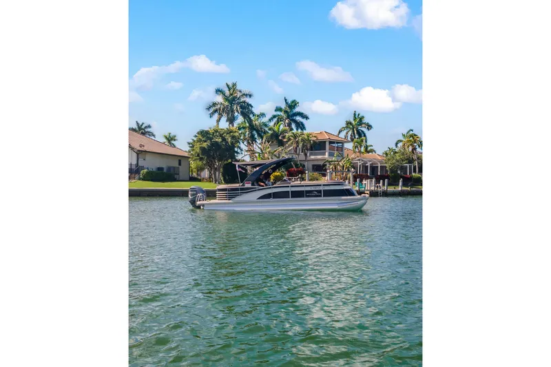 Slide: The Image of 2018 Bennington 25 QSR pontoon boat on a scenic waterfront with palm trees. - 10