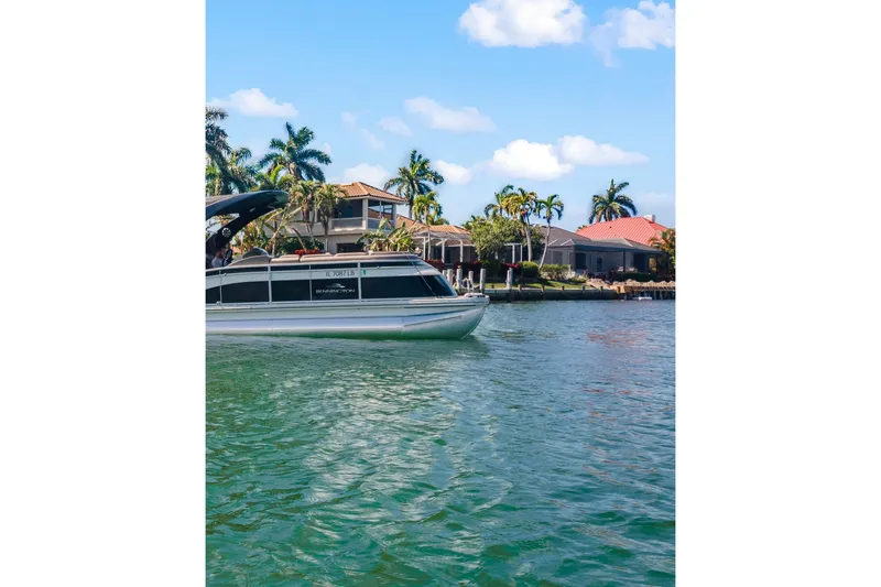 Slide: The Image of 2018 Bennington 25 QSR boat cruising near waterfront homes with palm trees. - 11