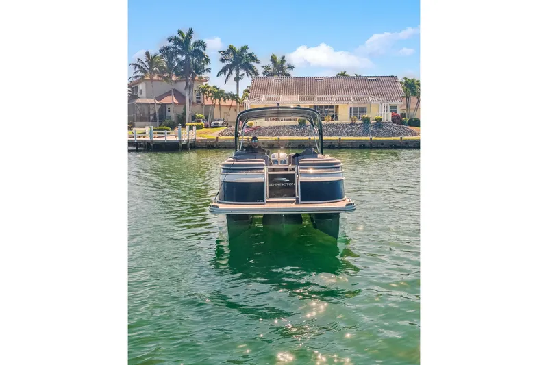 Slide: The Image of 2018 Bennington 25 QSR pontoon boat on a sunny waterfront with palm trees. - 17