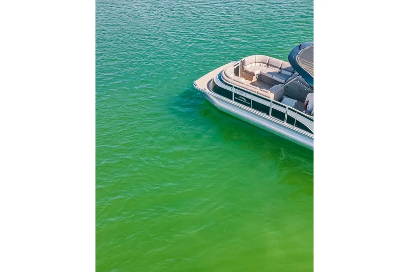 Slide: The Image of 2018 Bennington 25 QSR pontoon boat on vibrant green water. - 2
