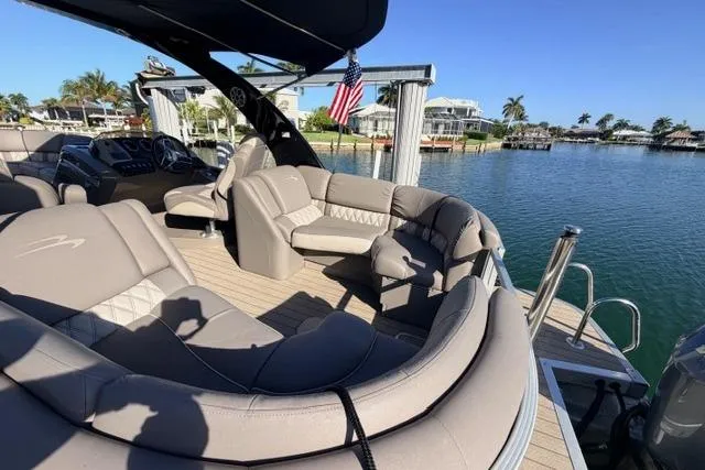 Slide: The Image of 2018 Bennington 25 QSR pontoon boat with luxurious seating, docked by a scenic waterfront. - 23