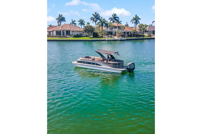 Slide: The Image of 2018 Bennington 25 QSR pontoon boat cruising on a scenic lake with waterfront homes. - 3