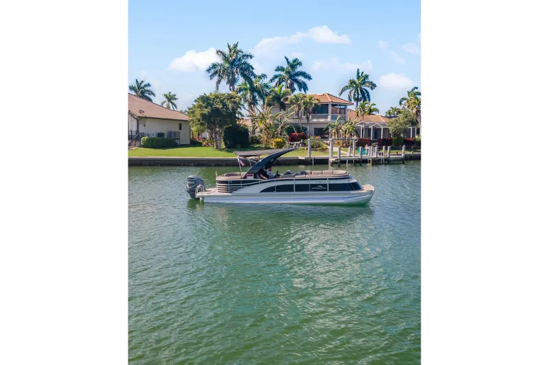 Slide: The Image of 2018 Bennington 25 QSR pontoon boat on a scenic waterfront with palm trees. - 9